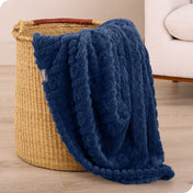 A sherpa blanket is hanging over the edge of a woven hamper