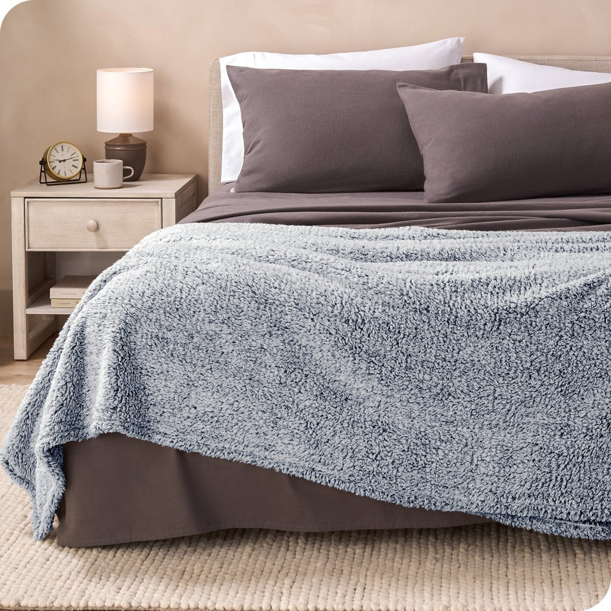 A textured sherpa blanket draped over the end and side of a bed