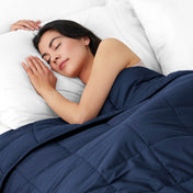 Woman sleeping peacefully under a weighted blanket with white pillows