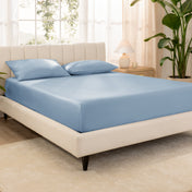 A bed made with an organic cotton sateen fitted sheet and matching pillowcases on pillows