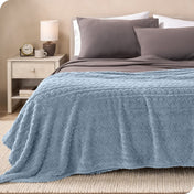 A textured sherpa blanket draped over the end and side of a bed