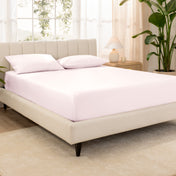 A bed made with an organic cotton sateen fitted sheet and matching pillowcases on pillows