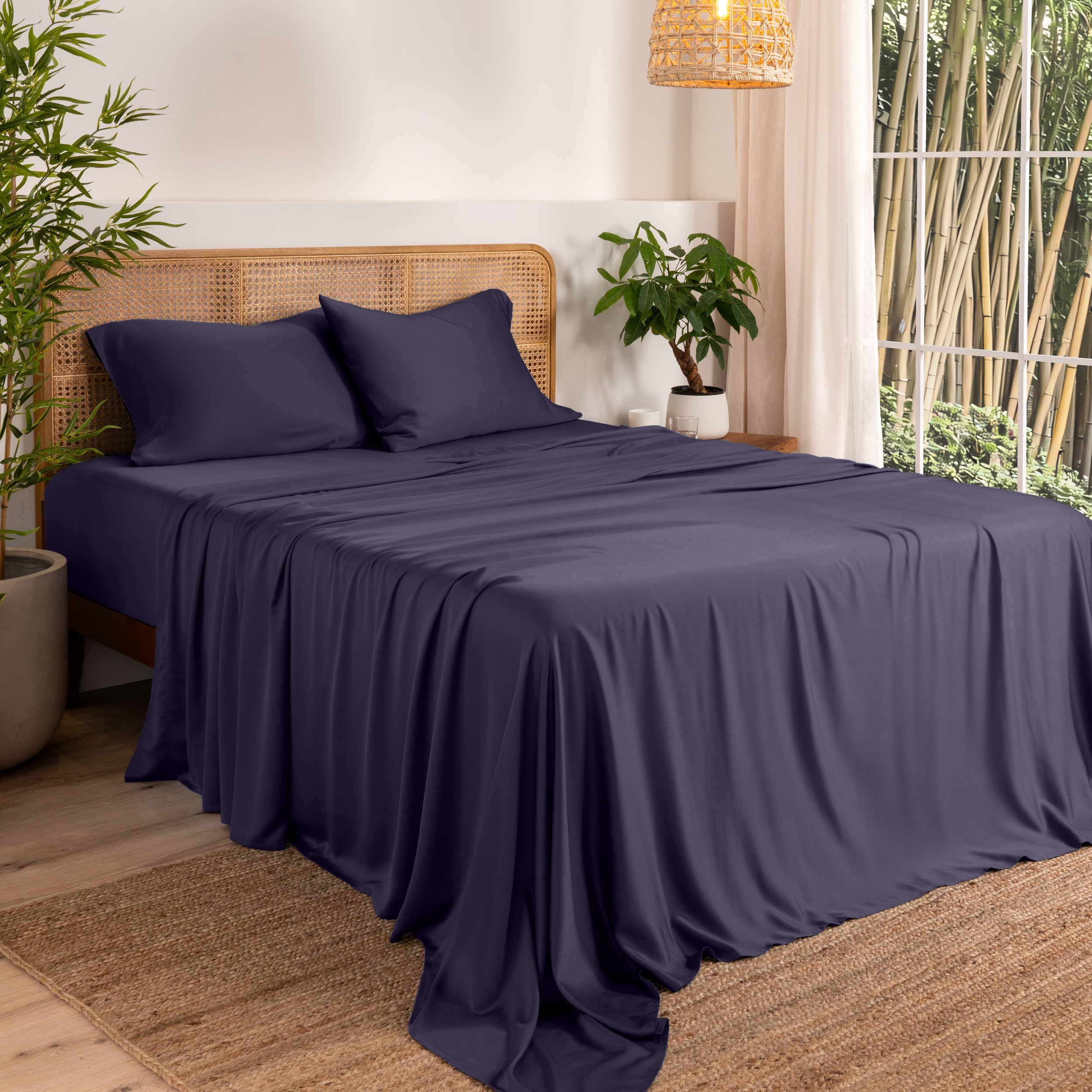 Bamboo sheets on a bed in a bedroom with plants and a lamp.