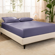 A bed made with an organic cotton sateen fitted sheet and matching pillowcases on pillows