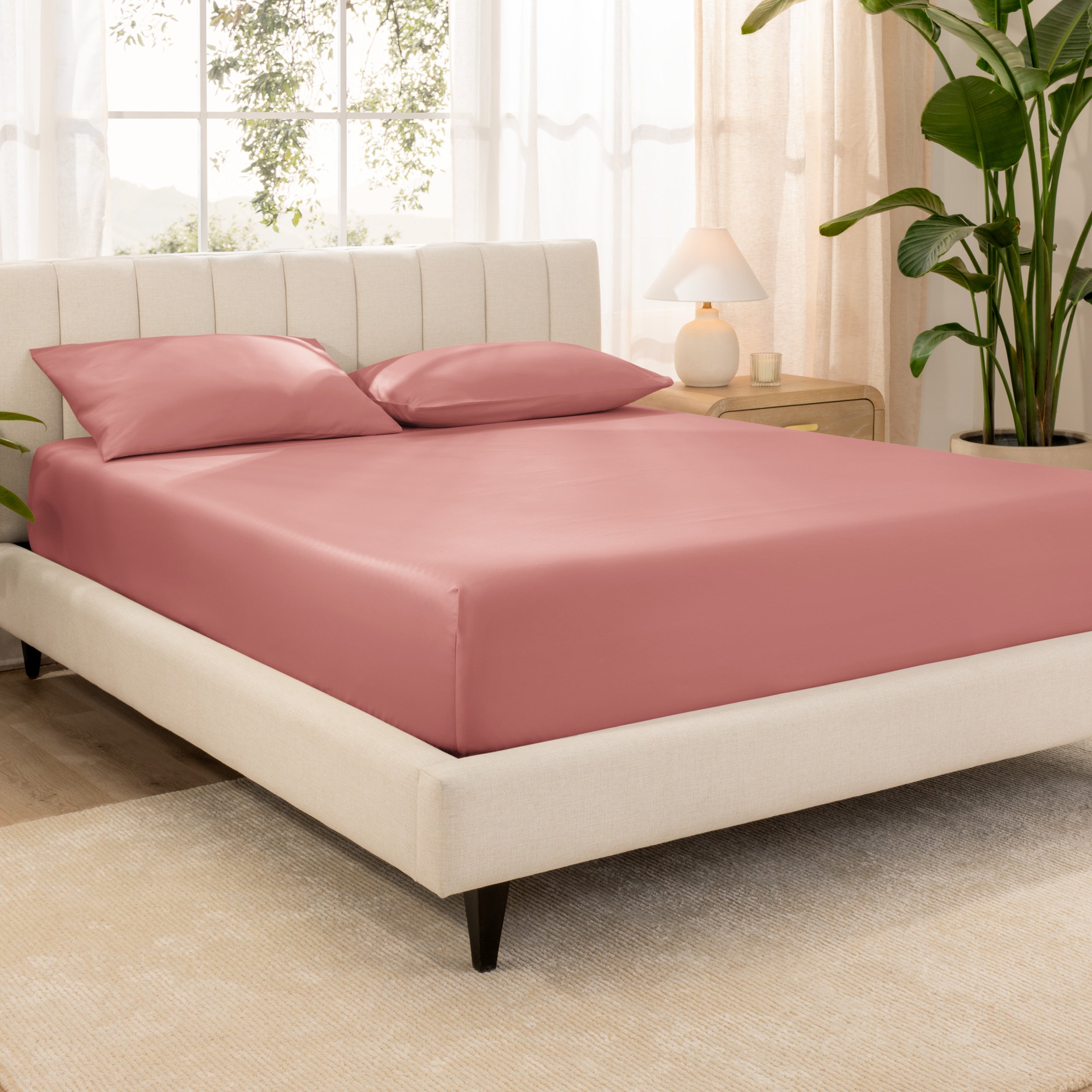 A bed made with an organic cotton sateen fitted sheet and matching pillowcases on pillows