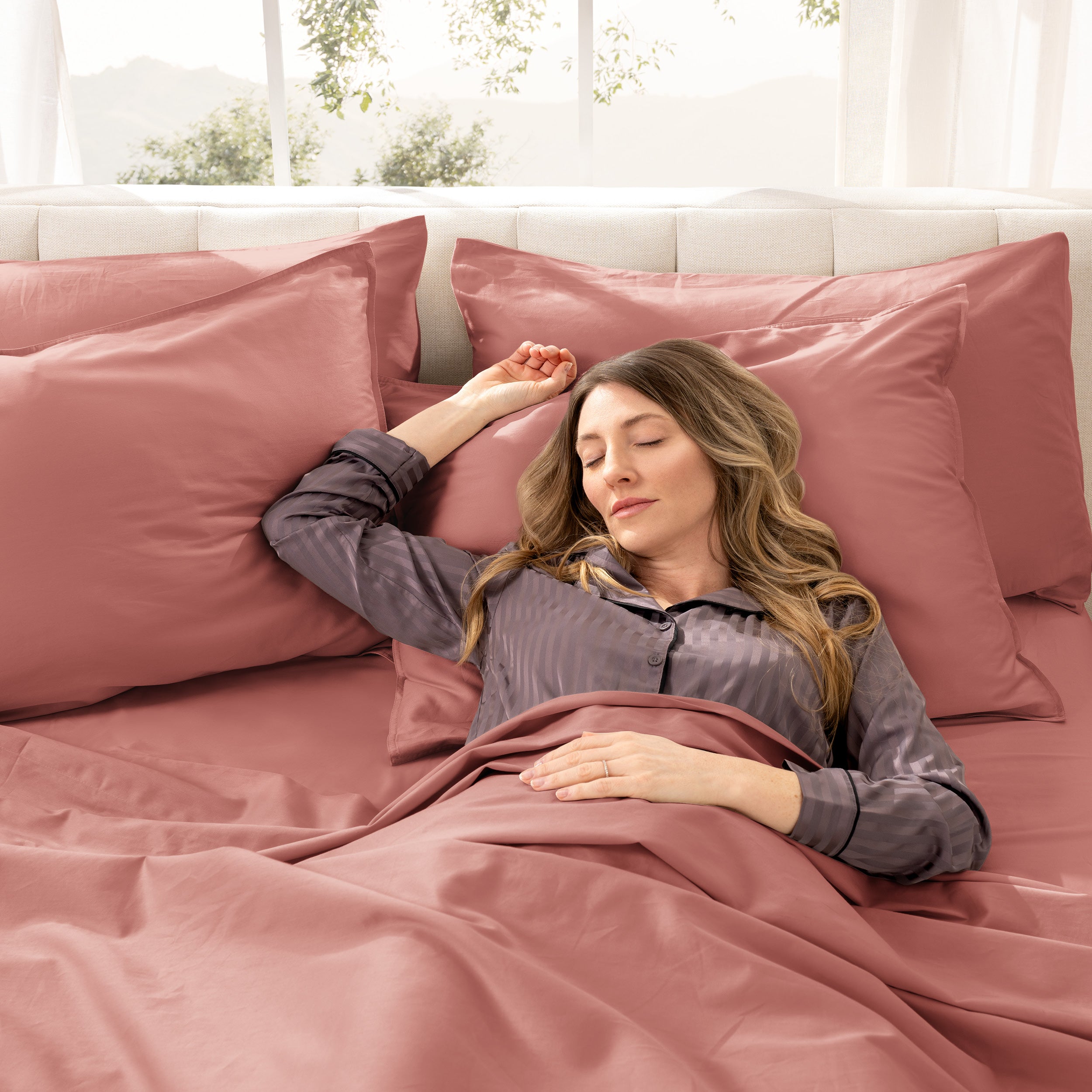A woman is sleeping on a bed made with organic cotton sateen sheets