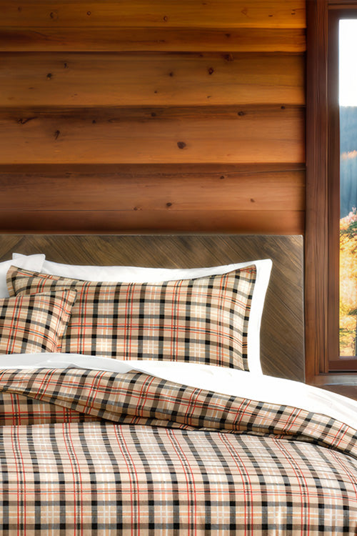 Plaid bedding set on a bed with wooden wall and window in the background