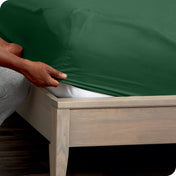 Person adjusting a fitted sheet on a mattress