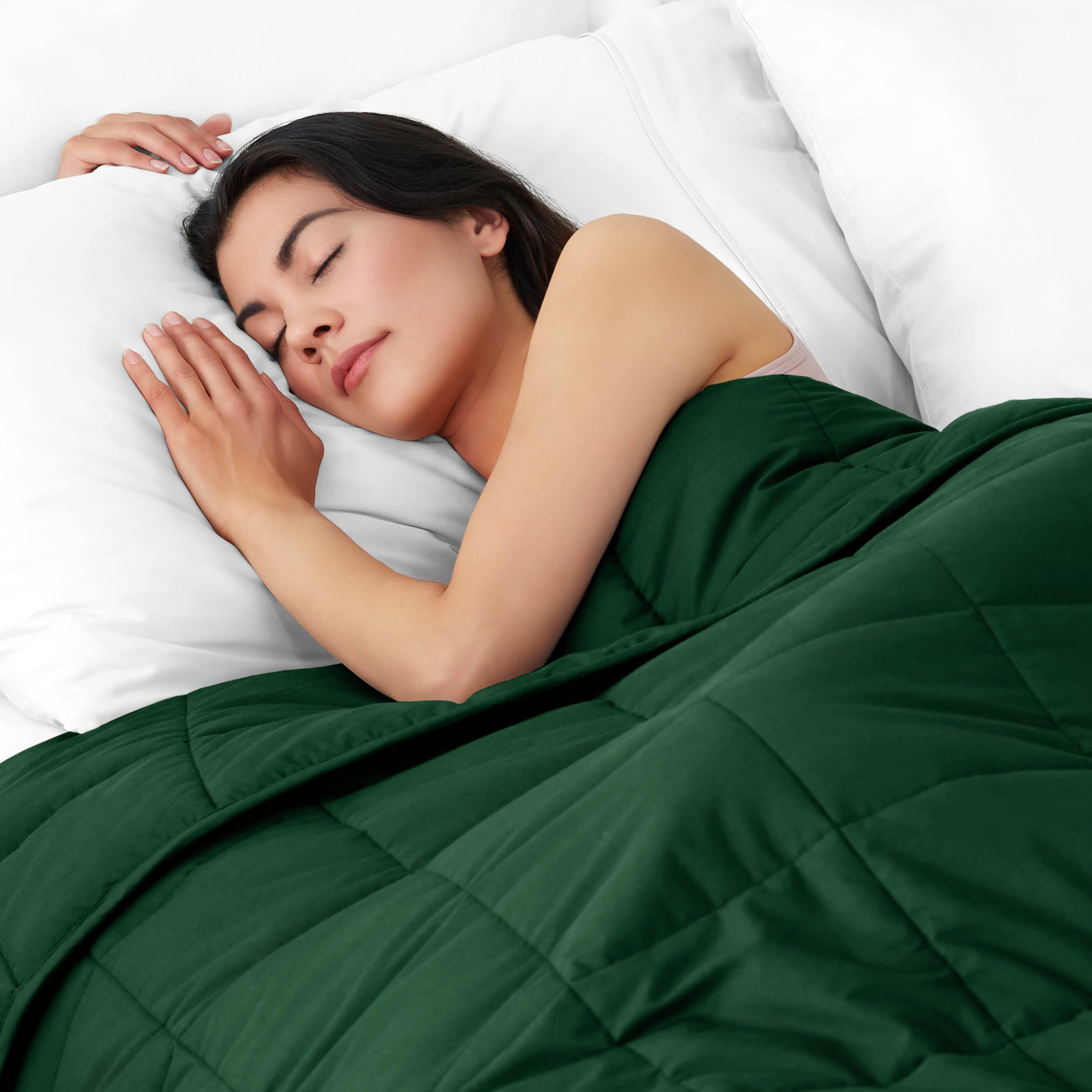 Woman sleeping peacefully under a weighted blanket with white pillows