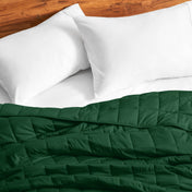 Cotton weighted blanket on a bed with white pillows against a wooden headboard.