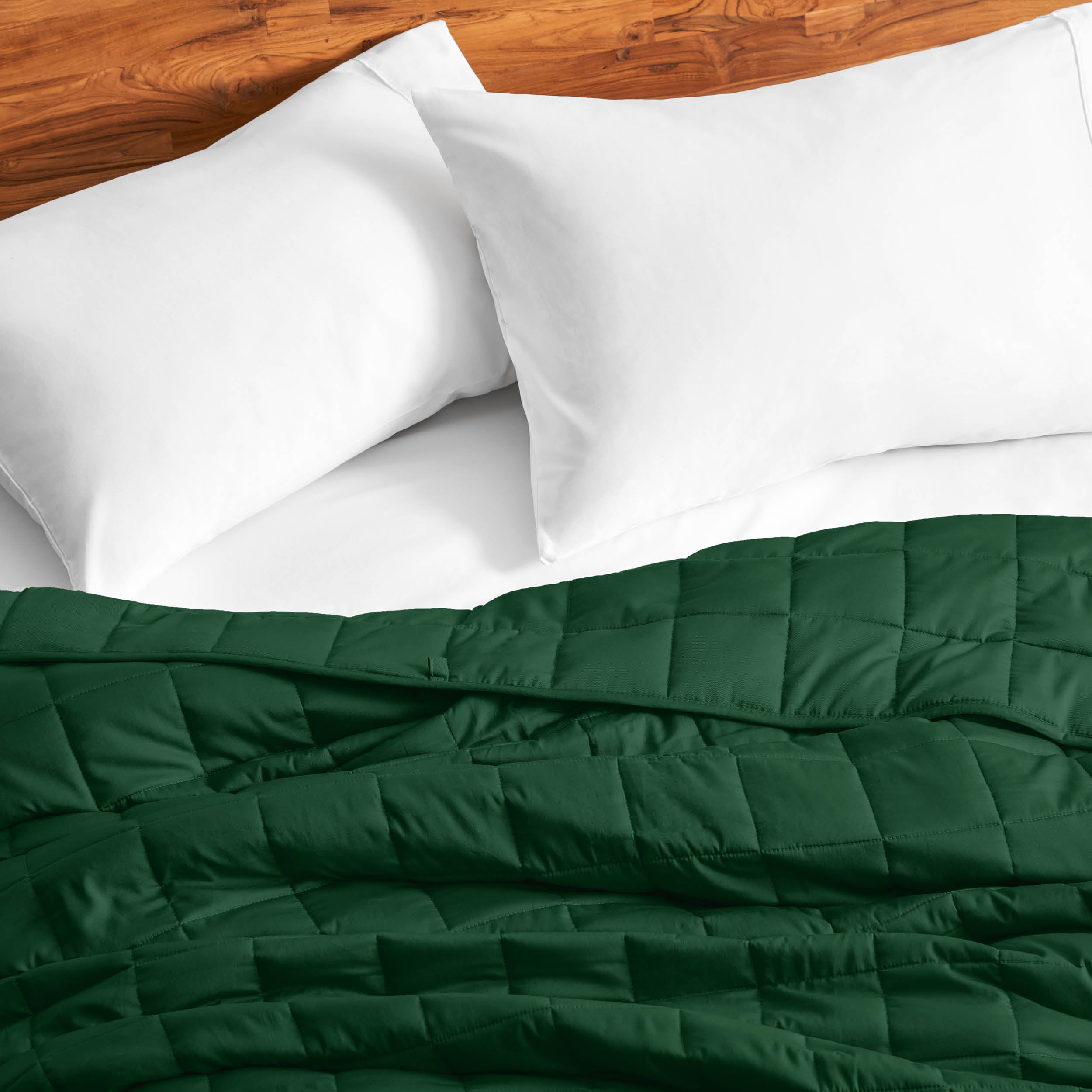 Cotton weighted blanket on a bed with white pillows against a wooden headboard.