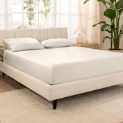 A bed made with an organic cotton sateen fitted sheet and matching pillowcases on pillows
