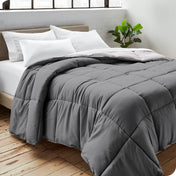 Close up of a comforter on a bed folded over itself. There are also 4 pillows on the bed.