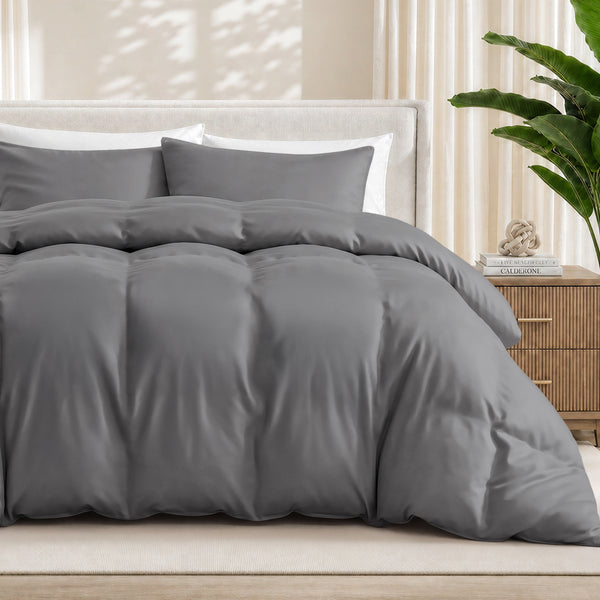 Grey duvet cover set on a bed in a bedroom setting with a plant and nightstand.