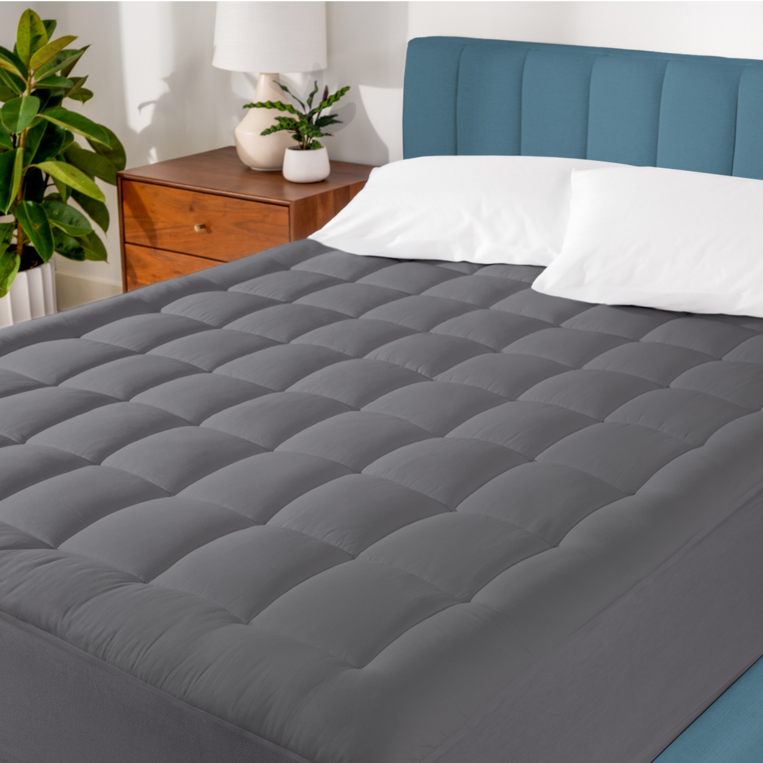 A cotton top mattress pad on a mattress in a modern bedroom.