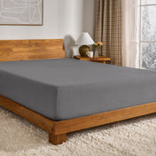Grey fitted sheet on a wooden bed in a bedroom setting