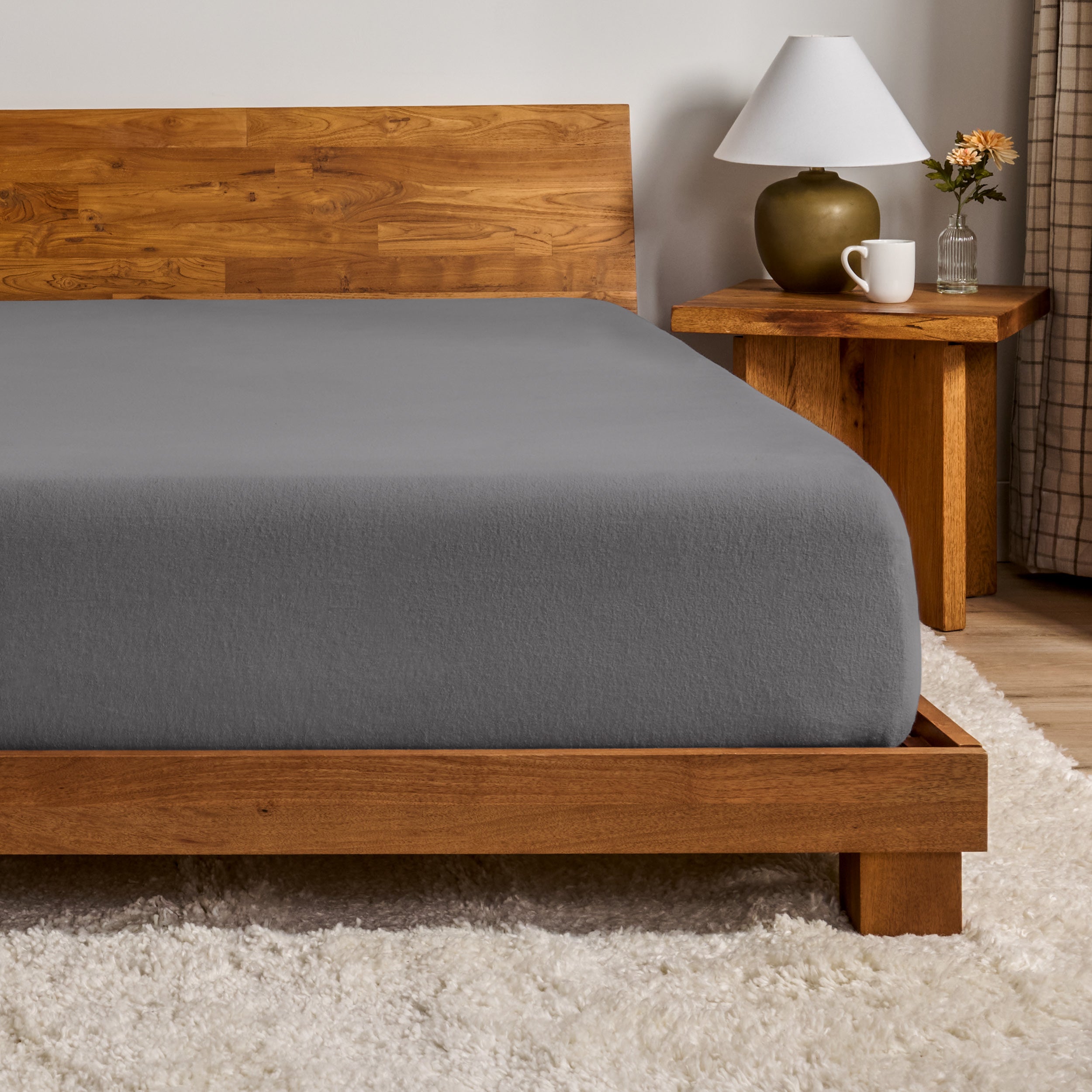 A flannel fitted sheet on a mattress with a wooden bed frame