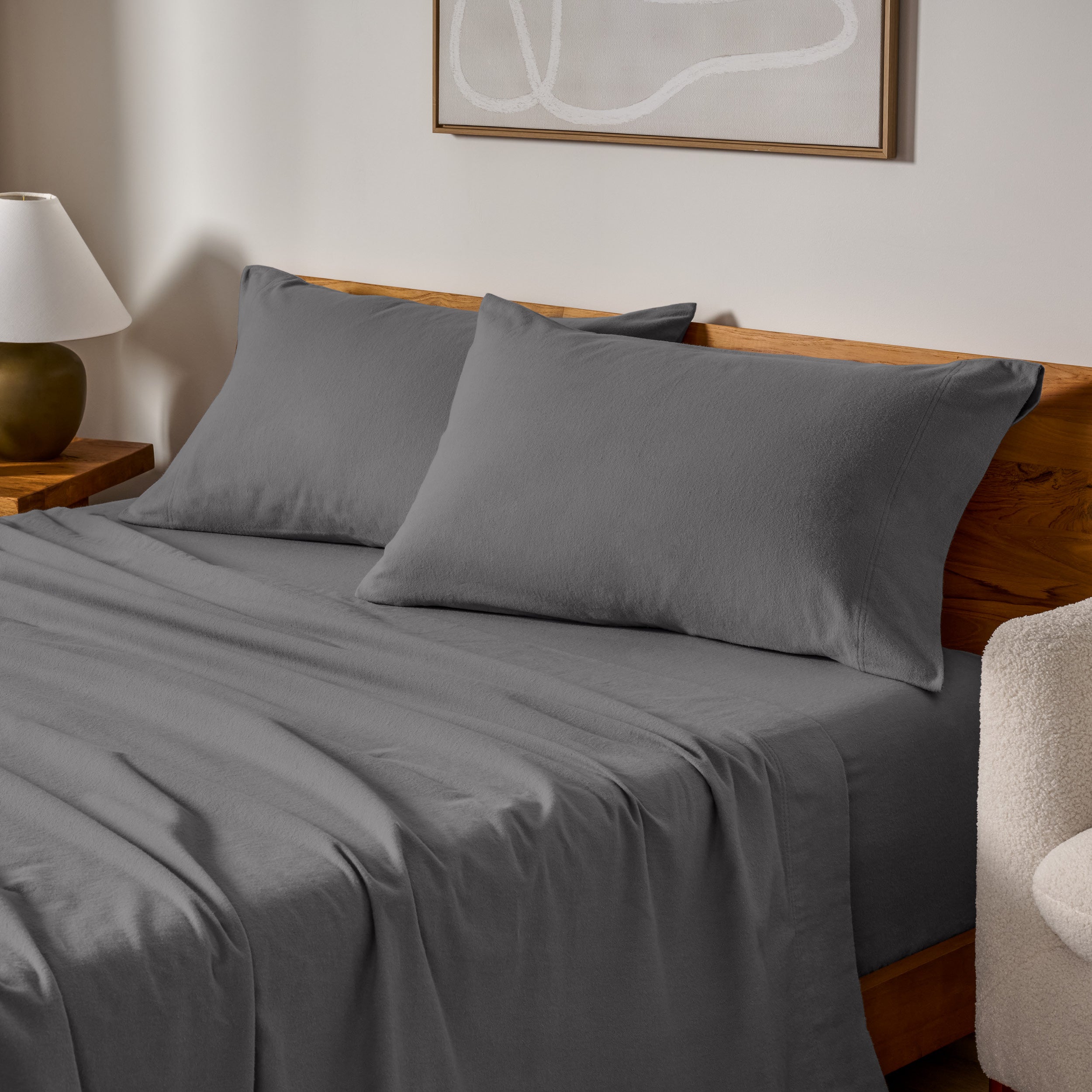 Cotton flannel sheets and pillows on a wooden bed in a bedroom setting.