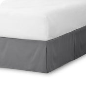 The corner of a bed skirt on a bed frame