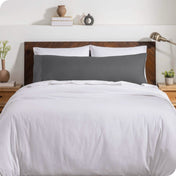 A body pillow cover on a pillow on a bed with other pillows and a duvet cover