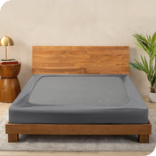 A cover on a box spring set on a wooden bed frame