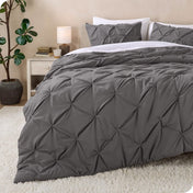 A bed made with a grey pintuck comforter set