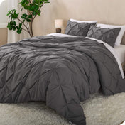 A side view of a bed with a grey pintuck comforter set draped over it