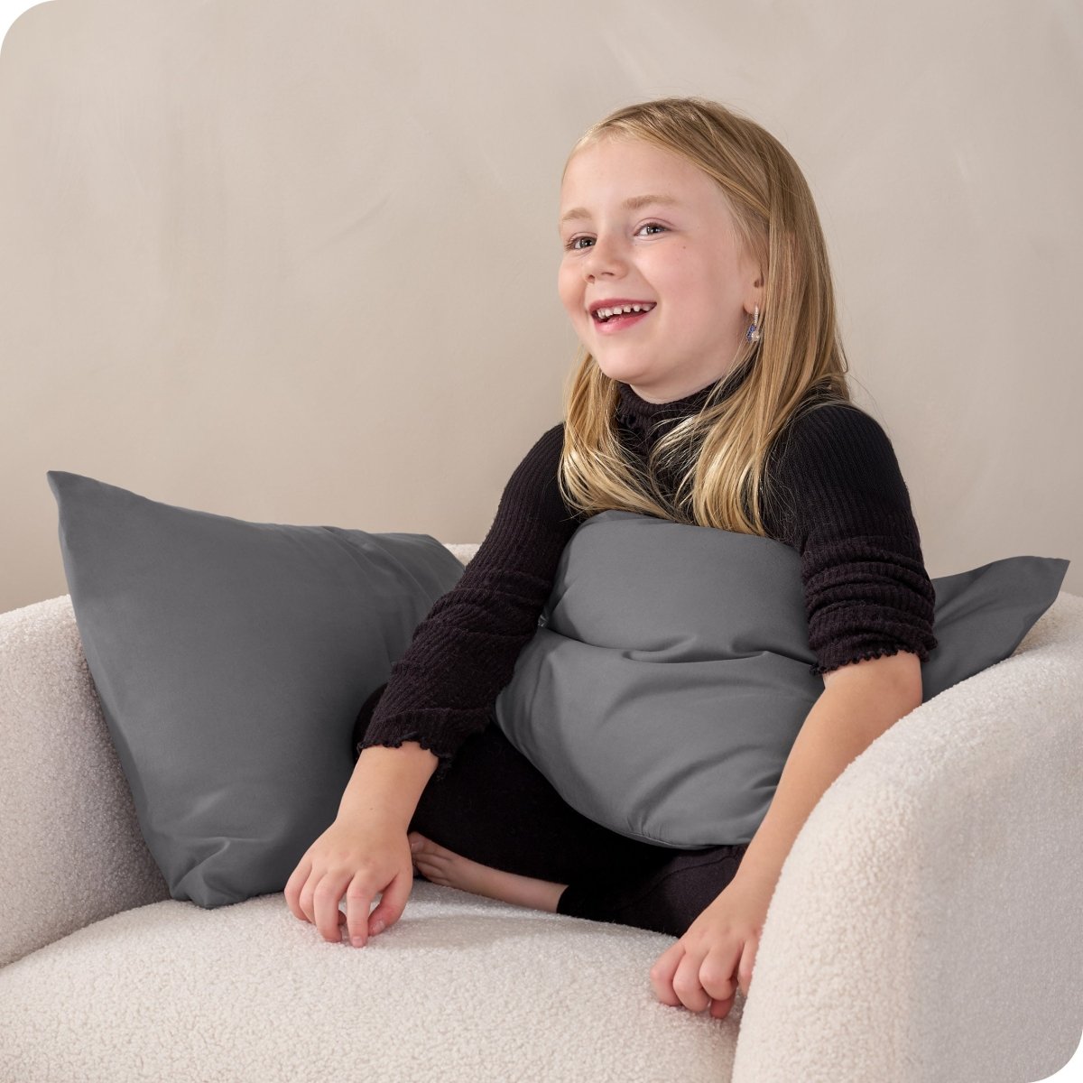 A child sitting while holding a microfiber pillowcase covered pillow