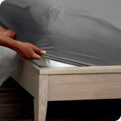 Person adjusting a fitted sheet on a mattress