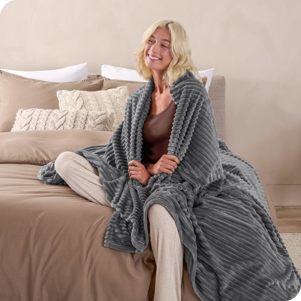 A man sitting on a bed wrapped in a microplush blanket
