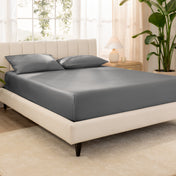 A bed made with an organic cotton sateen fitted sheet and matching pillowcases on pillows