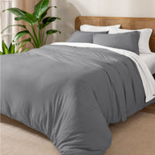 A cozy bed dressed in white sheets and pillows, complemented by an organic cotton jersey duvet cover set.