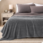 A textured sherpa blanket draped over the end and side of a bed