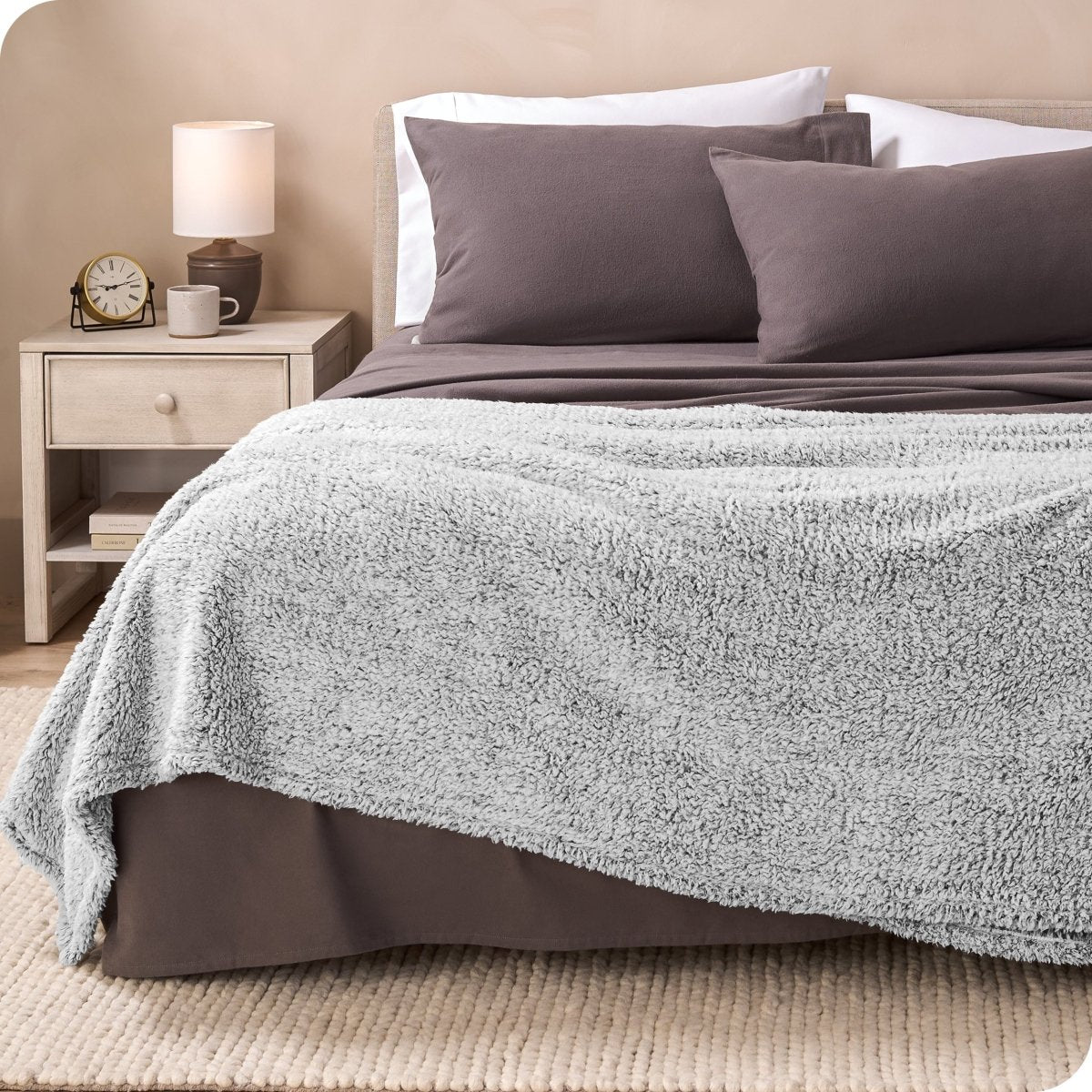 A textured sherpa blanket draped over the end and side of a bed