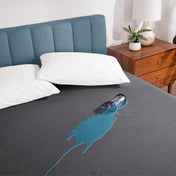 A glass of water spilled on a bed covered with a mattress protector