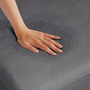 A woman is pressing her hand down a mattress with a terry cotton mattress protector on it