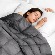 Woman sleeping peacefully under a weighted blanket with white pillows