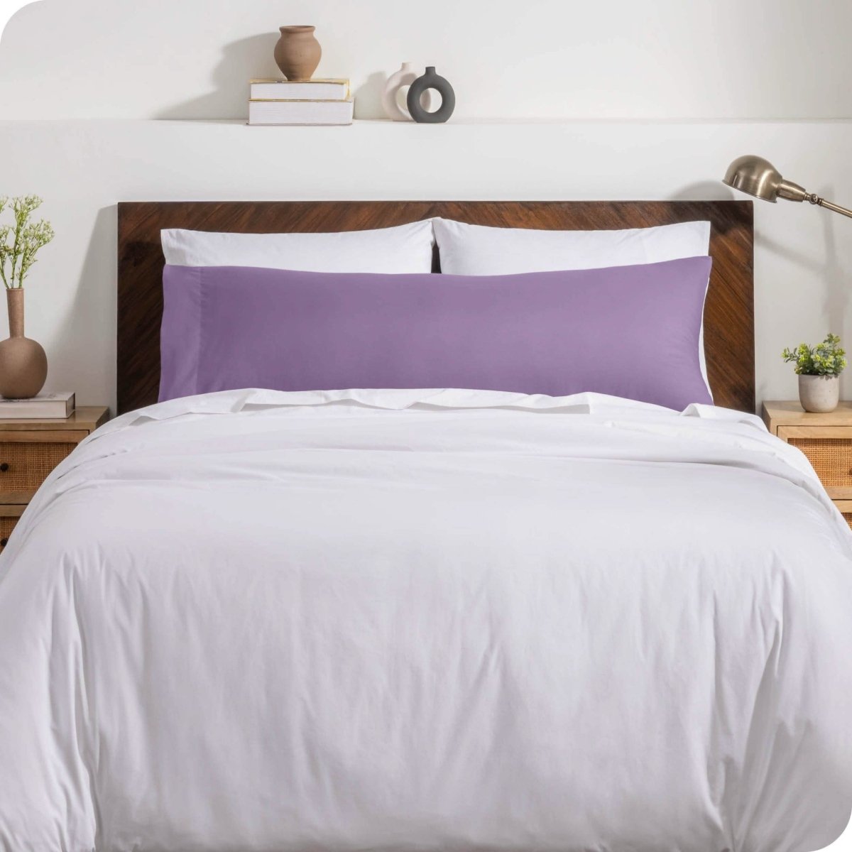 A body pillow cover on a pillow on a bed with other pillows and a duvet cover