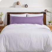 A body pillow cover on a pillow on a bed with other pillows and a duvet cover