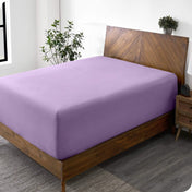 A diagonal view of a bed with just a fitted sheet on it