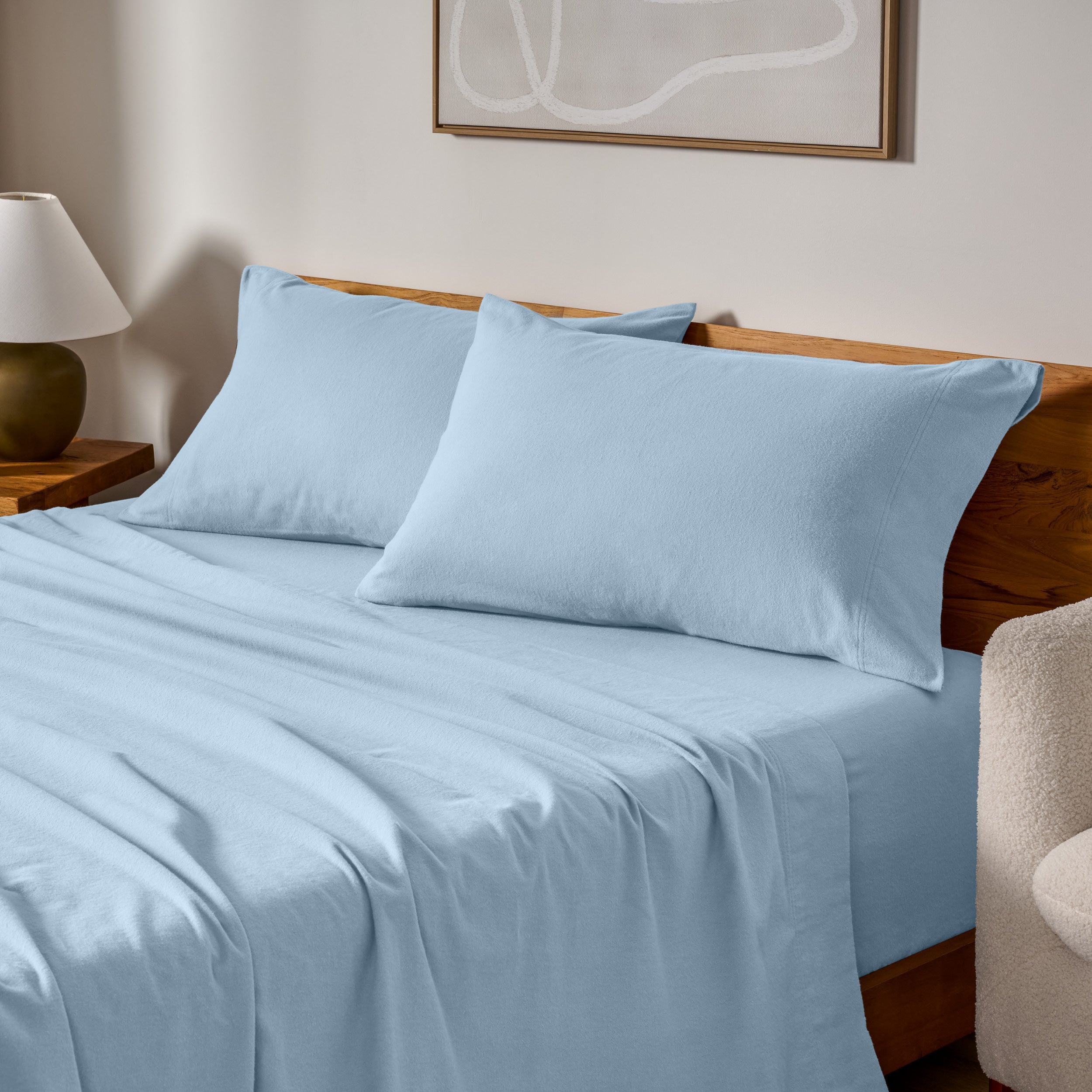 Cotton flannel sheets and pillows on a wooden bed in a bedroom setting.