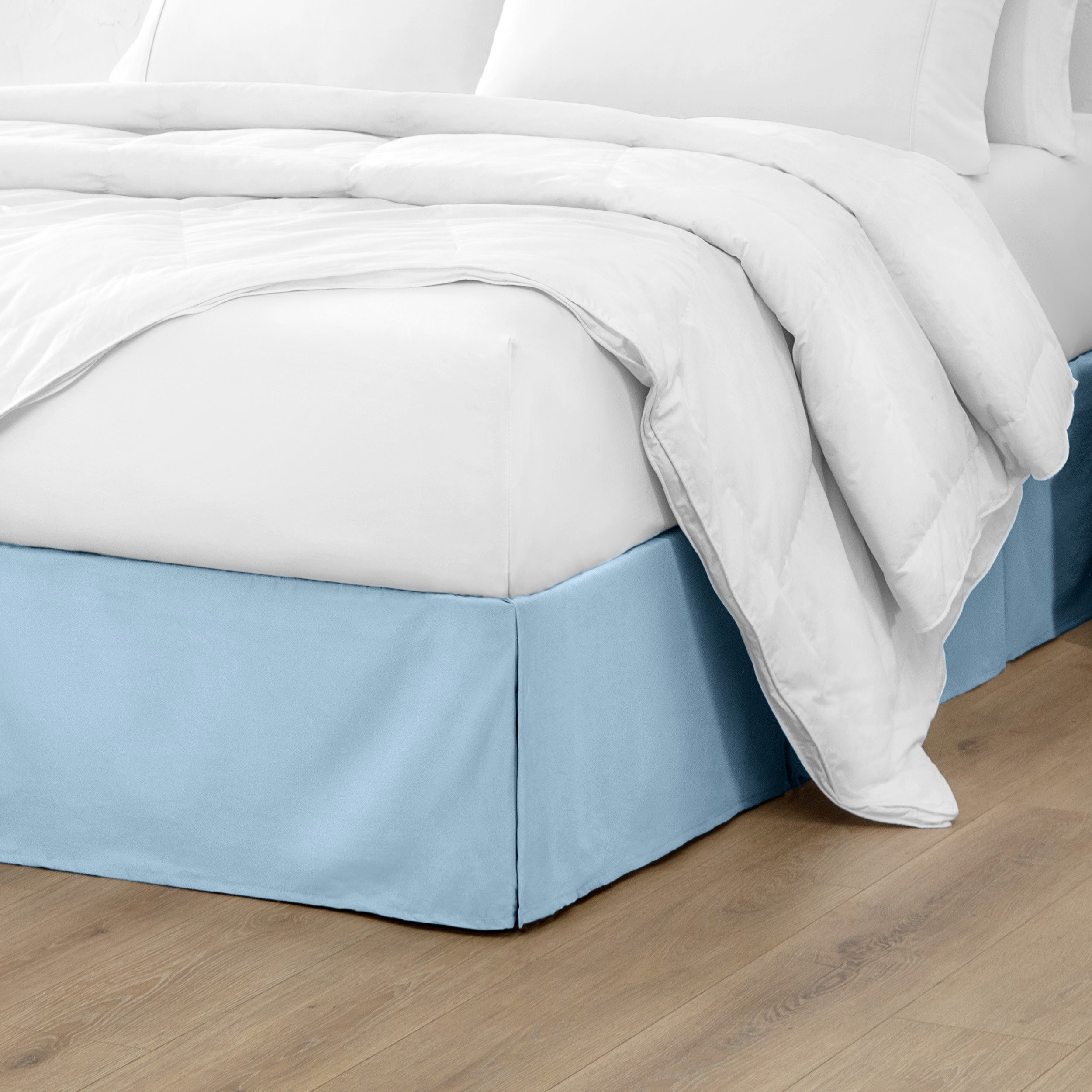 A modern bed with a microfiber bed skirt with pleats on the corners and midway on each side