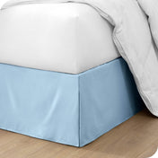 The corner of a bed with a bed skirt and comforter on it
