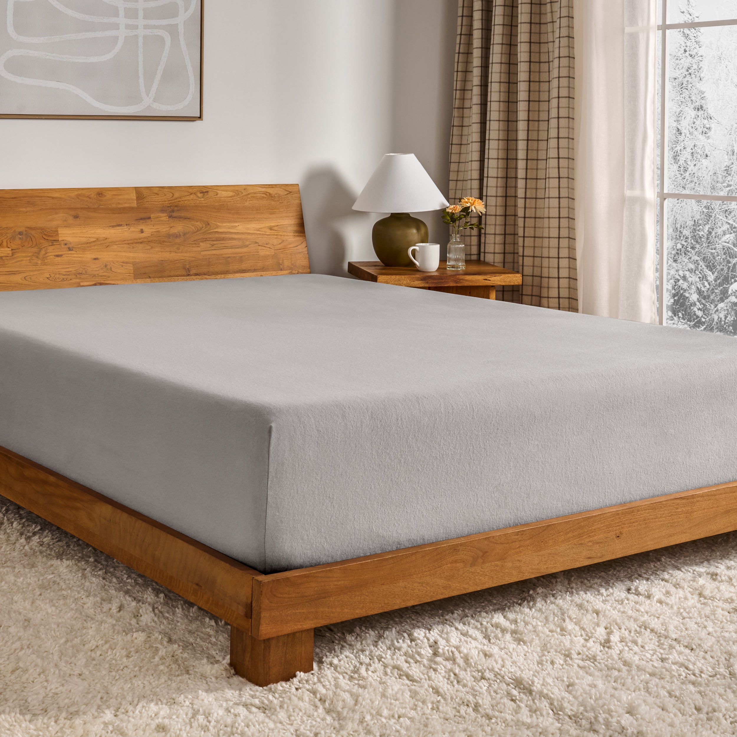 Grey fitted sheet on a wooden bed in a bedroom setting