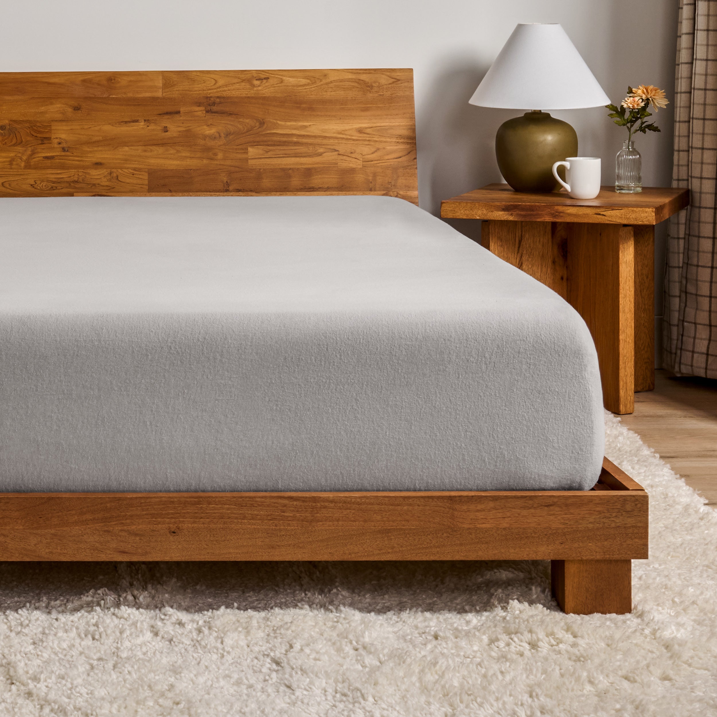 A flannel fitted sheet on a mattress with a wooden bed frame