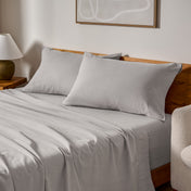 Cotton flannel sheets and pillows on a wooden bed in a bedroom setting.