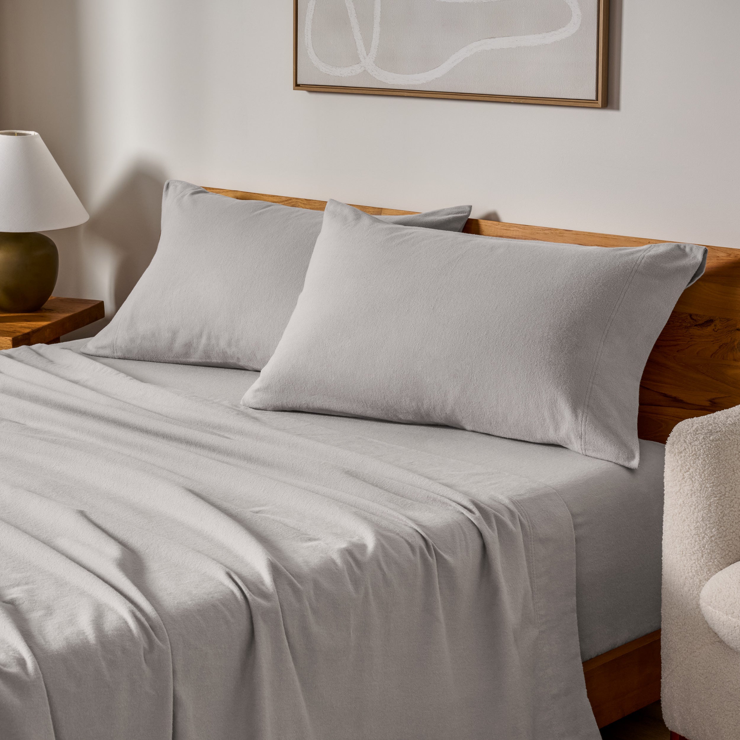 Cotton flannel sheets and pillows on a wooden bed in a bedroom setting.