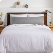 A body pillow cover on a pillow on a bed with other pillows and a duvet cover
