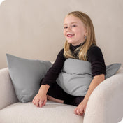 A child sitting while holding a microfiber pillowcase covered pillow