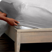 Person adjusting a fitted sheet on a mattress